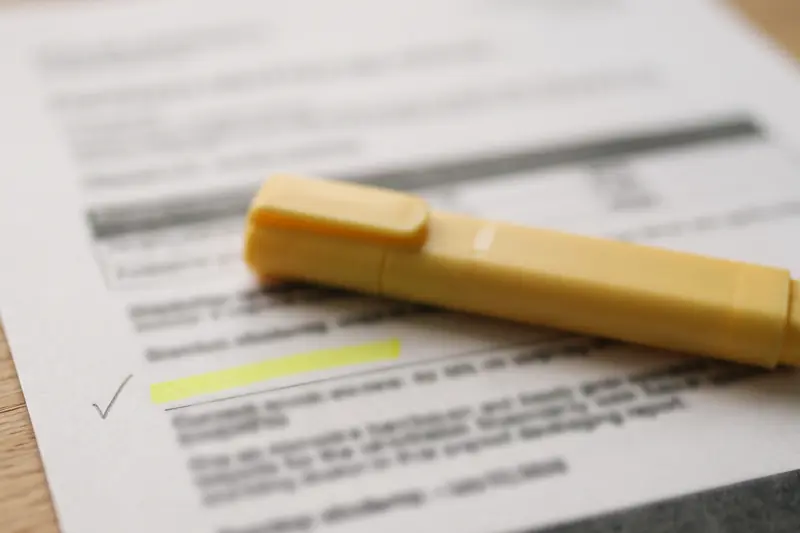 Une page de rapport imprimée, un passage surligné en jaune et une coche au crayon dans la marge.